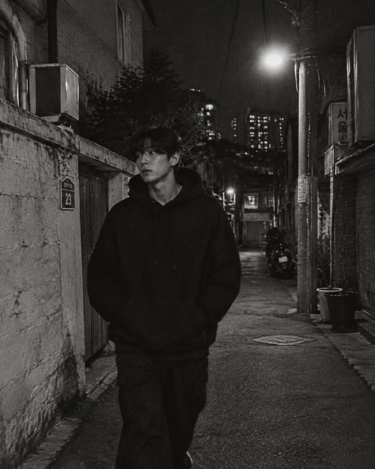 A lone figure walking through a Seoul alley at night
